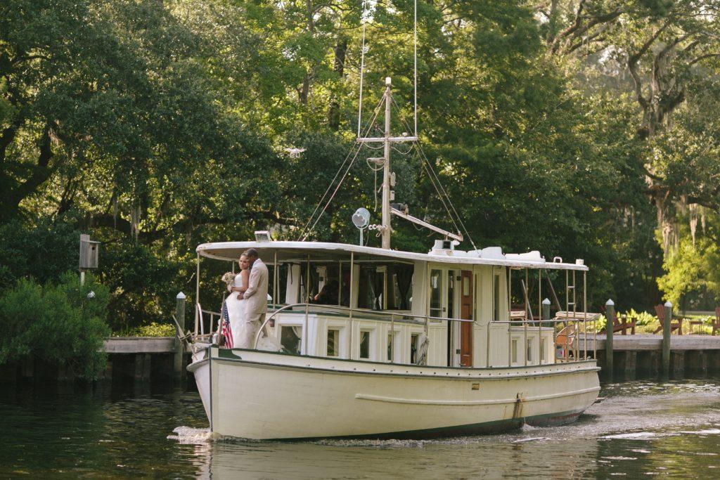 A bride and groom stand on the bow of a fishing boat on the bayou behind Palmetto's on the Bayou in Louisiana.