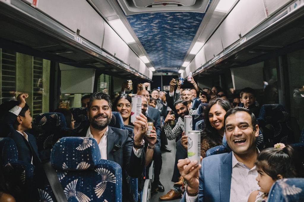 Wedding guests celebrate on a charter bus transporting them to wedding festivities. | photo by Rare Sighting Photography