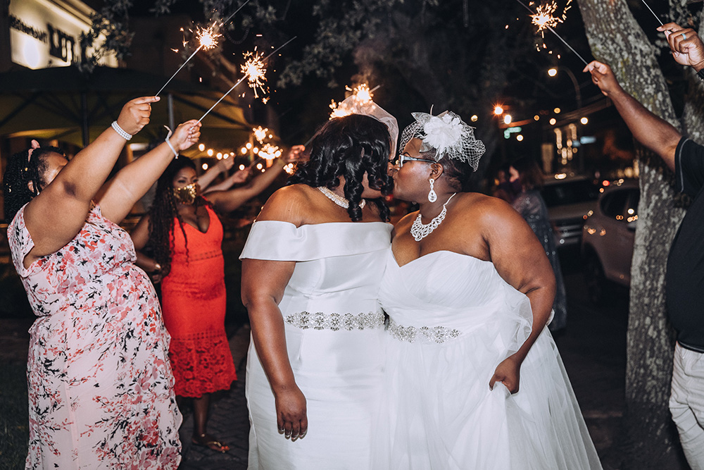 The brides kiss during their sparkler exit.