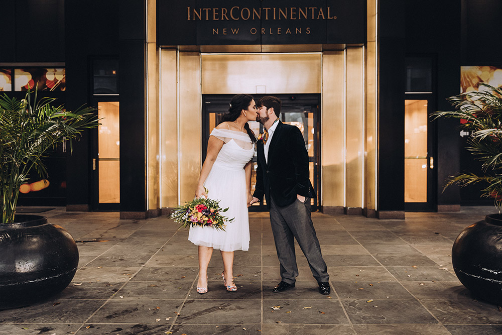 The bride and groom kiss outside the InterContinental New Orleans Hotel entrance.