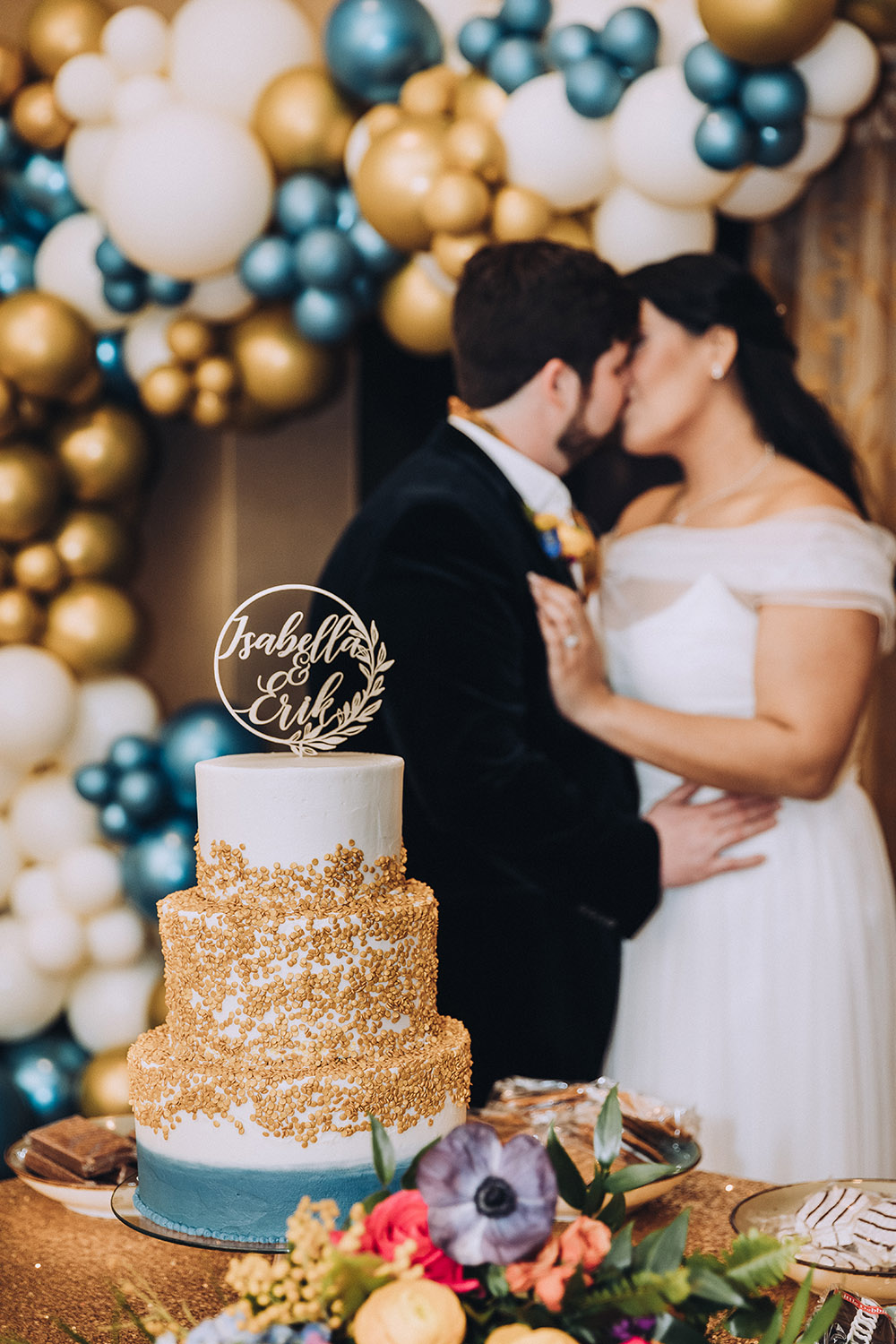 The bride and groom kiss by the wedding cake