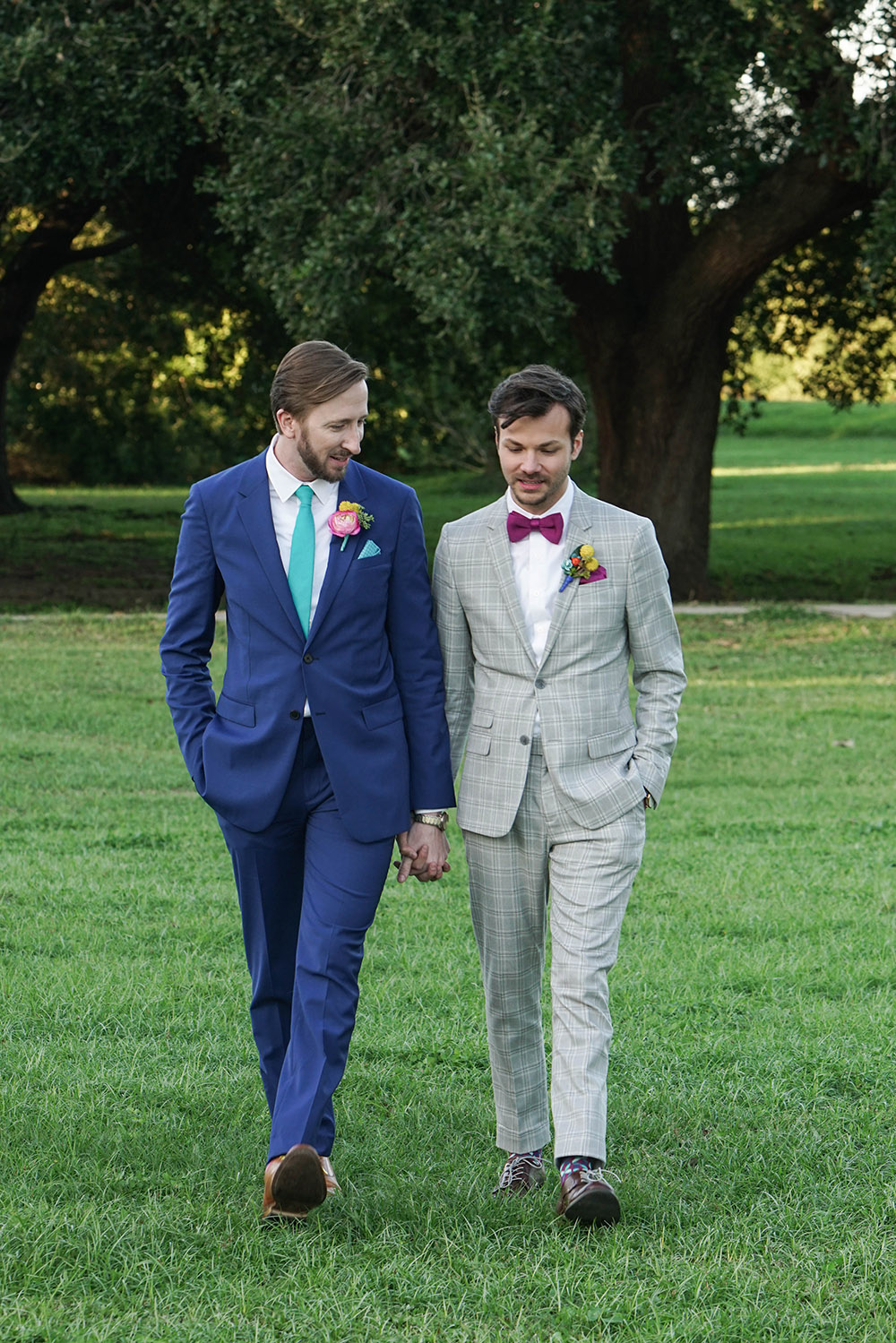 the grooms walk through New Orleans City Park holding hands