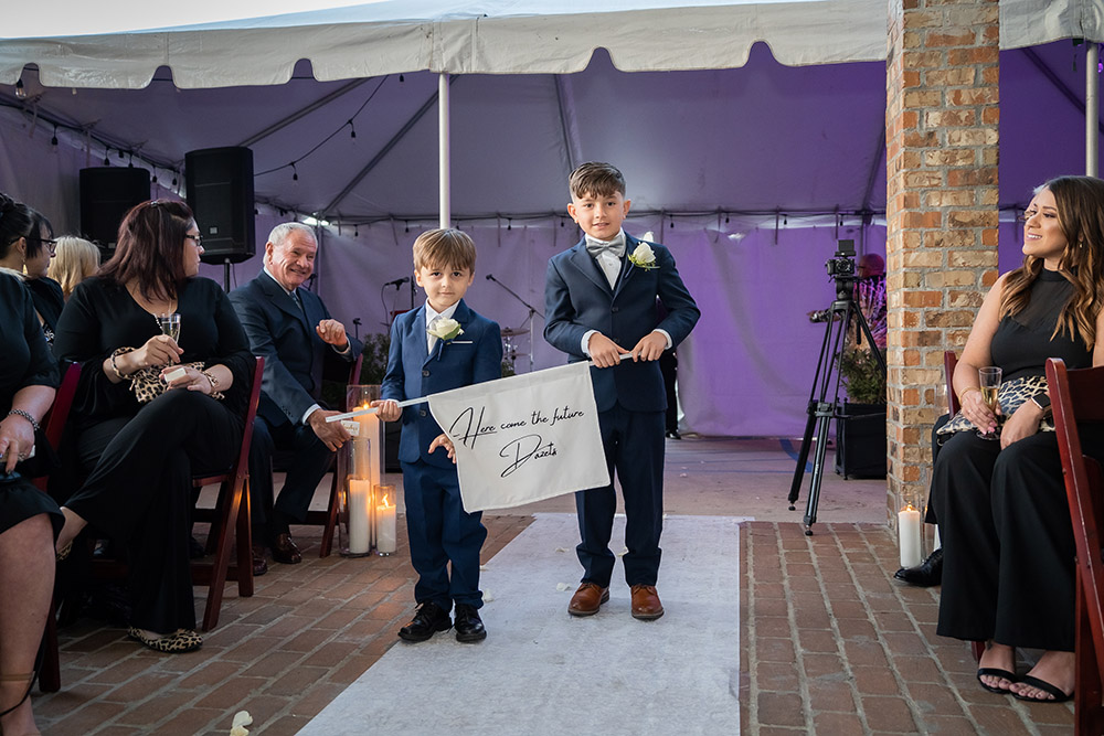 the ring bearers carry a sign announcing the brides