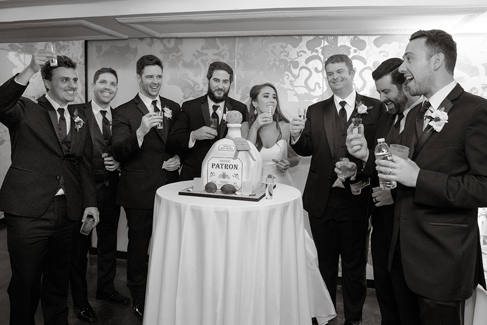 the groomsmen take patron shots at the groom's cake.