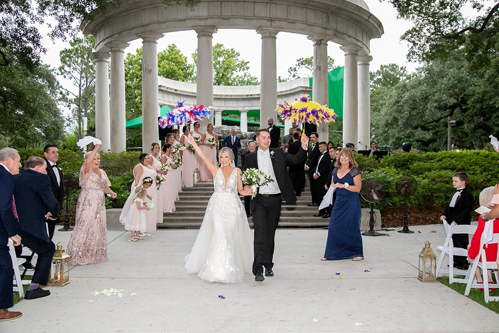 the bride and groom walk back up the aisle with second line umbrellas