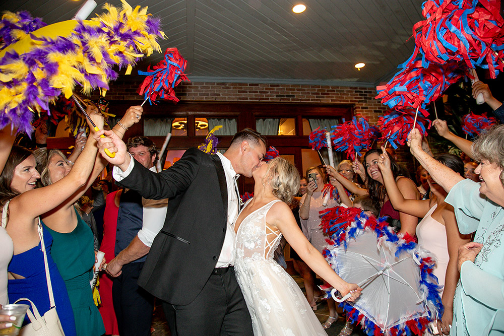 The wedding exit with pom poms from the bride and groom's favorite team colors, LSU purple and gold and Ole Miss Red and Blue