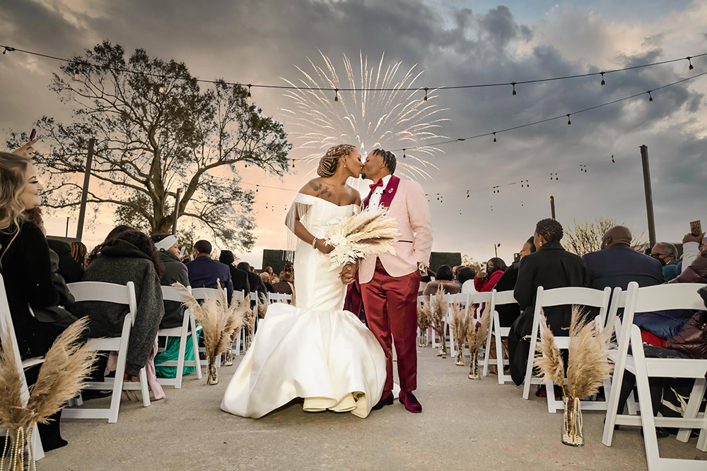 Bride and groom kiss with wedding fireworks in the background