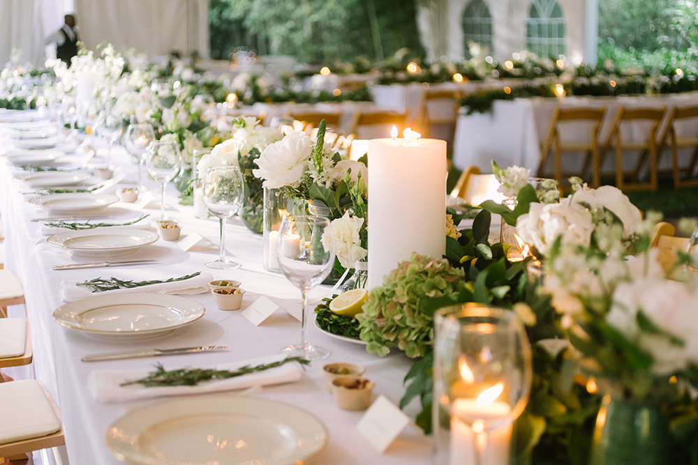 wedding reception table set with candles and greenery decor