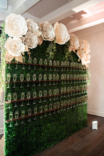 Nola Grace Decor's champagne hedge wall with paper flowers. Photo: Brocato Photography Collective