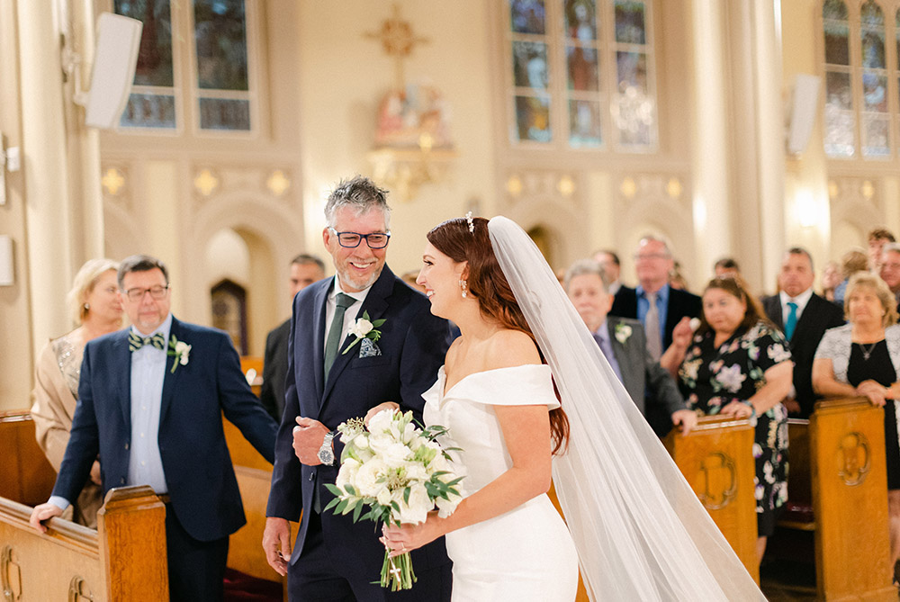 the bride's father walks her down the aisle at Holy Name of Jesus Church
