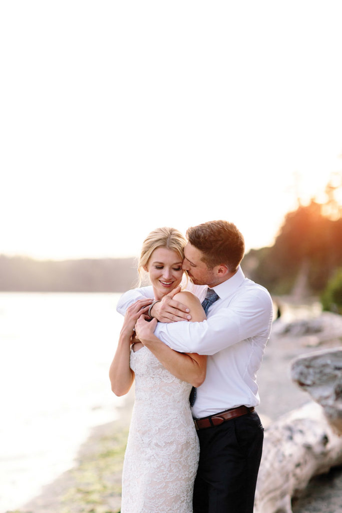 bride and groom embrace on the shoreline | photo by Sarah Alleman Photography